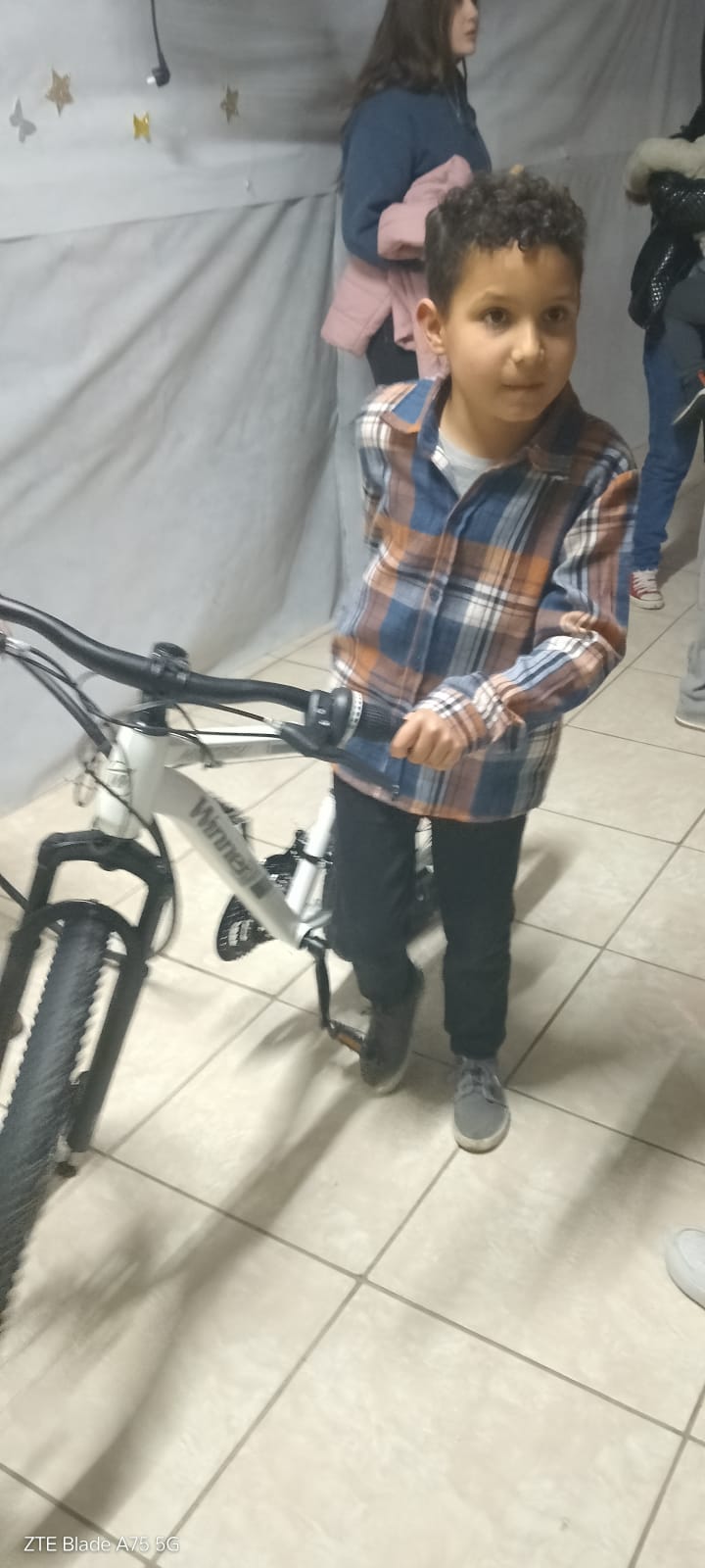 Niño sonriente con la bicicleta ganada en los sorteos.